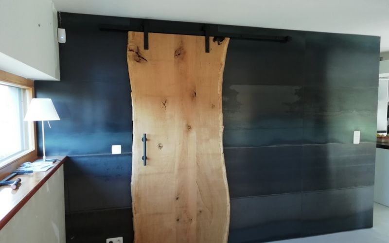 Habillage d'un mur avec de l'acier brut et porte coulissante en chêne à ANLIER